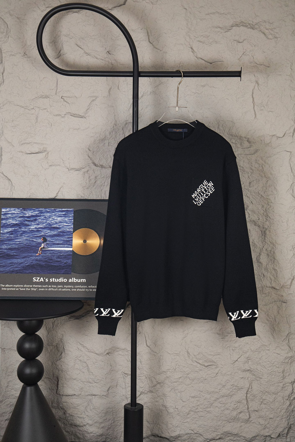 Black long-sleeve knit sweater with small chest logo on hanger