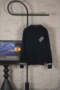 Black long-sleeve knit sweater with small chest logo on hanger