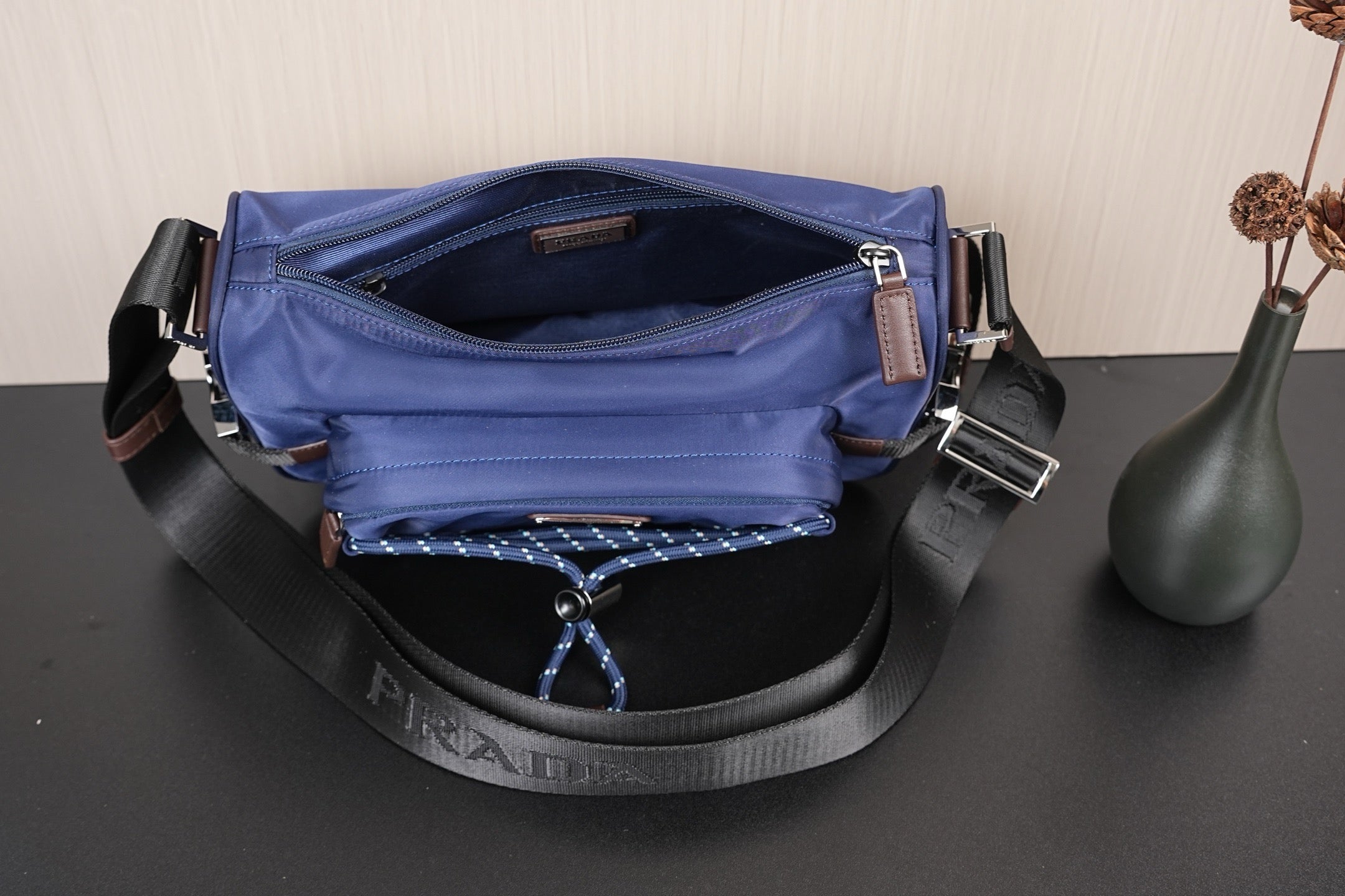 Open dark blue Prada crossbody bag showing interior lining and D-ring hardware