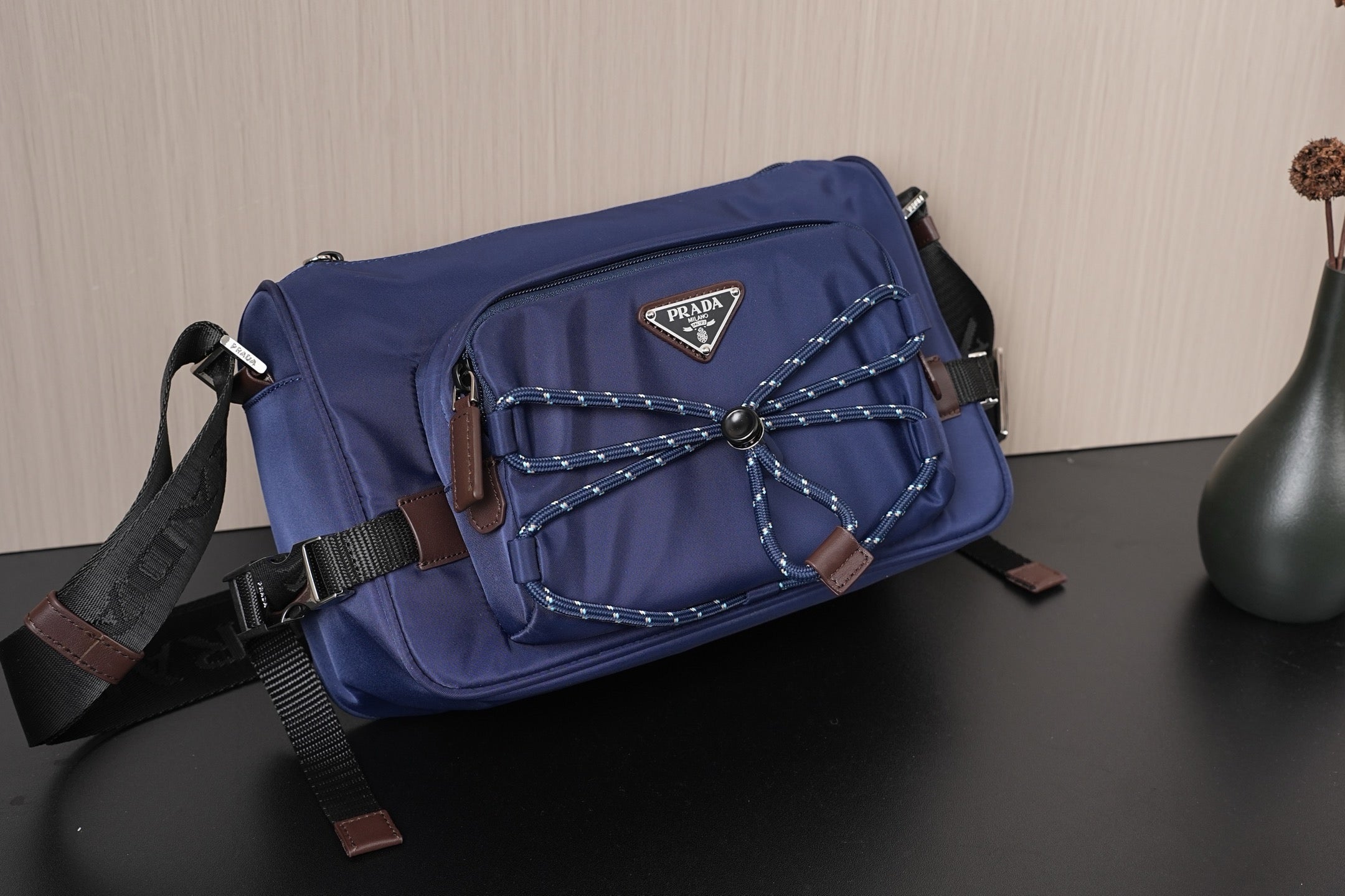 Dark blue Prada crossbody bag with braided decorative cords and front triangular logo