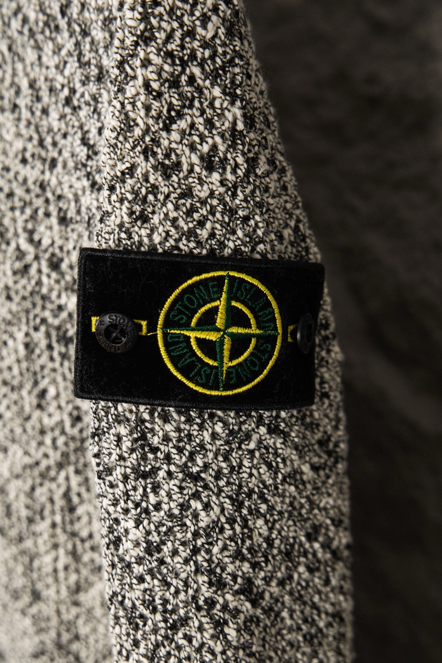 Stone Island logo patch on flecked jacket, black label with yellow emblem