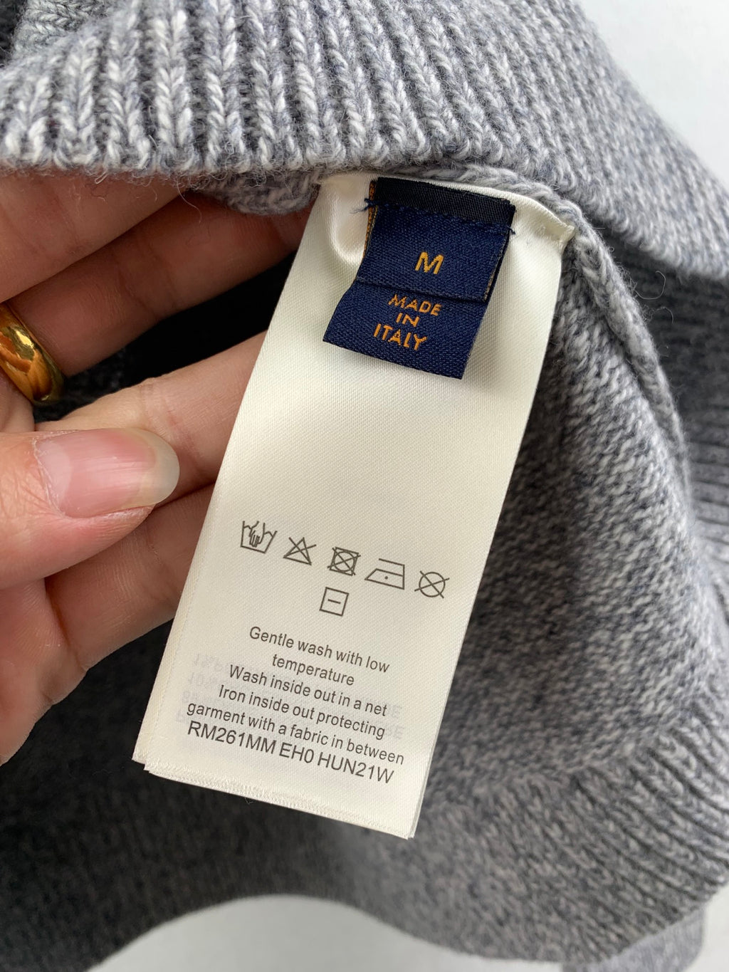 Grey knit sweater tag on inner neckline, with size M and care icons