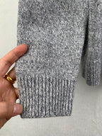 Grey knit sweater hem and ribbed cuffs, held by hand