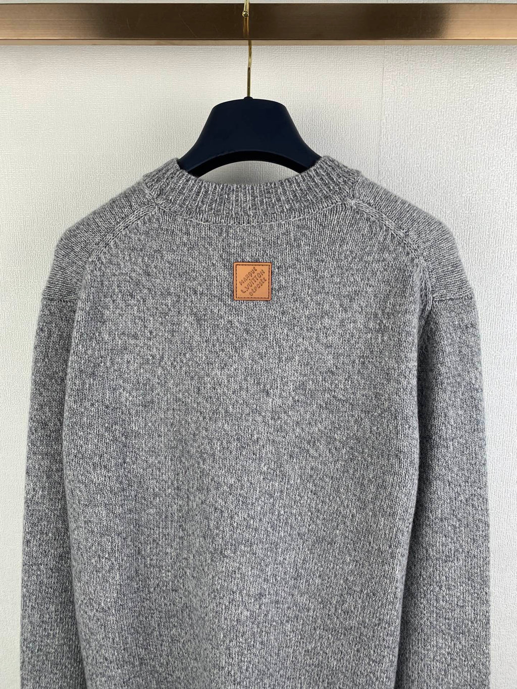 Grey knit sweater back neckline with small leather-style patch