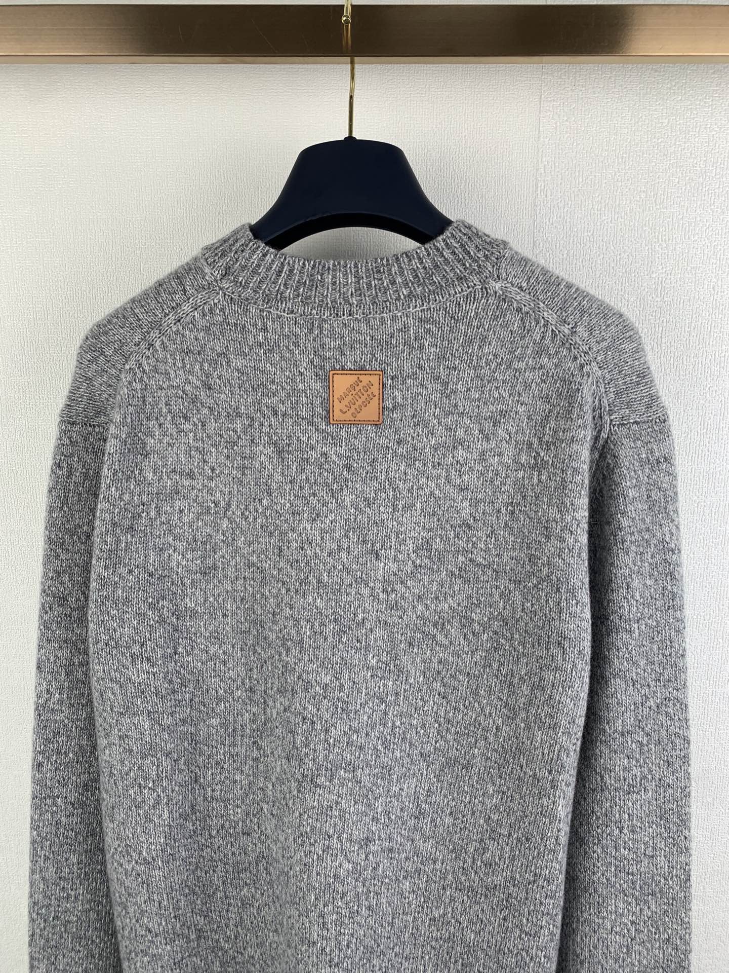 Grey knit sweater back neckline with small leather-style patch