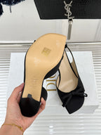Black heeled sandal with bow at toe and beige outsole underside