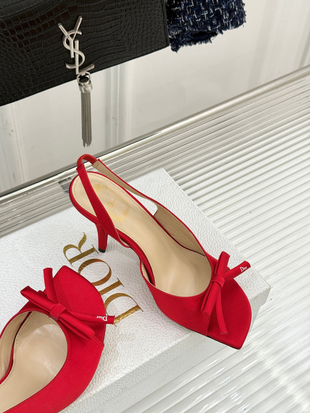 Red stiletto slingback pumps with bow ties, angled view on white display