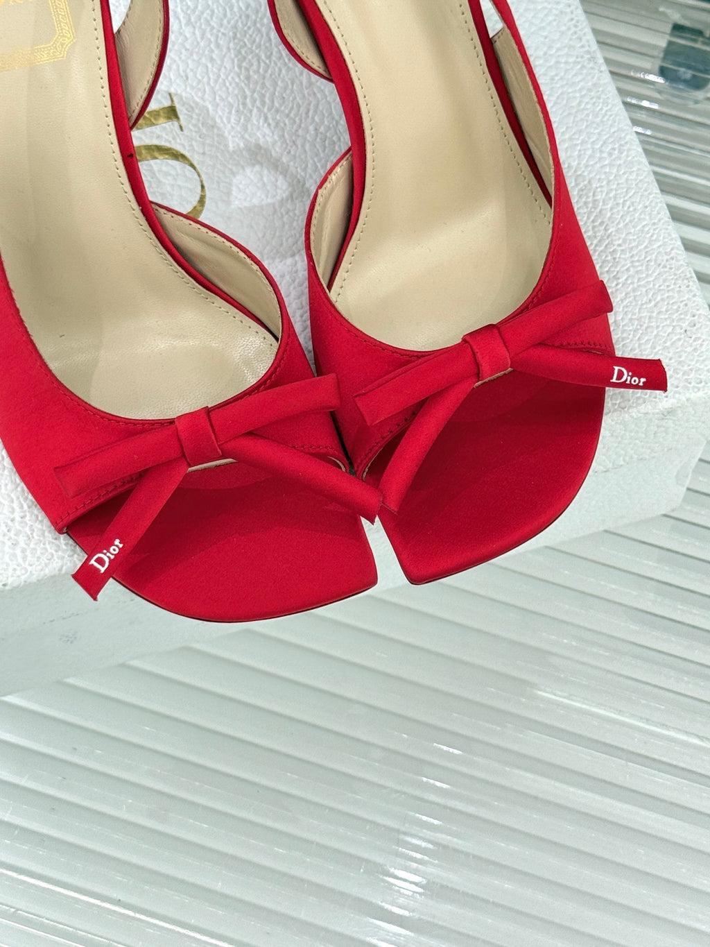 Close-up of red stiletto slingback pumps with bow ties and beige lining