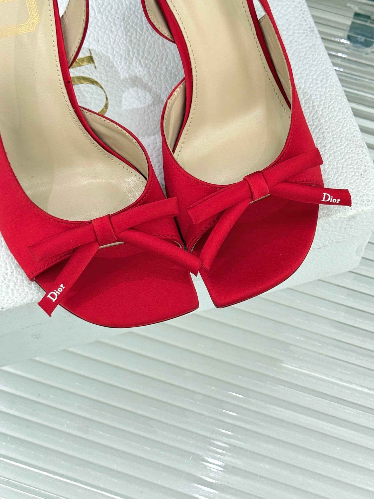 Close-up of red stiletto slingback pumps with bow ties and beige lining