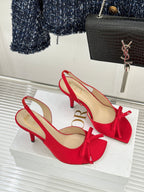Red stiletto slingback pumps with bow ties, side view on white display