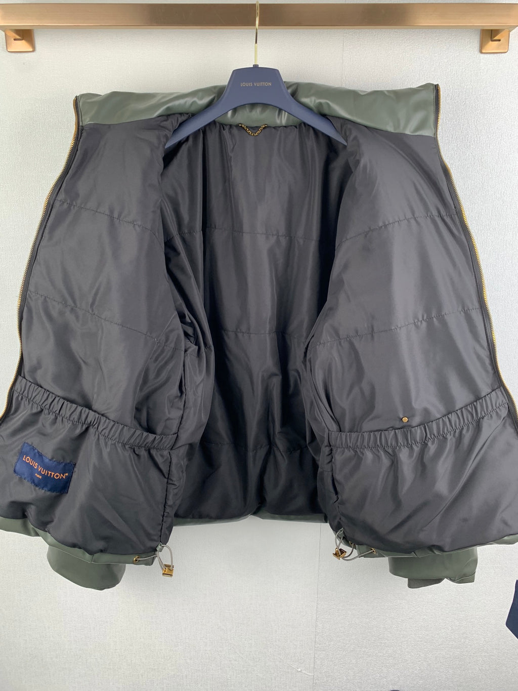 Long hooded puffer jacket with two-tone dark and olive-gray body and elastic hem