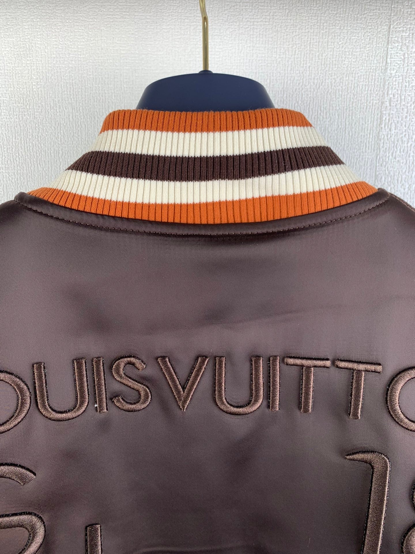 Dark long jacket with striped knit hood trim and Louis Vuitton logo