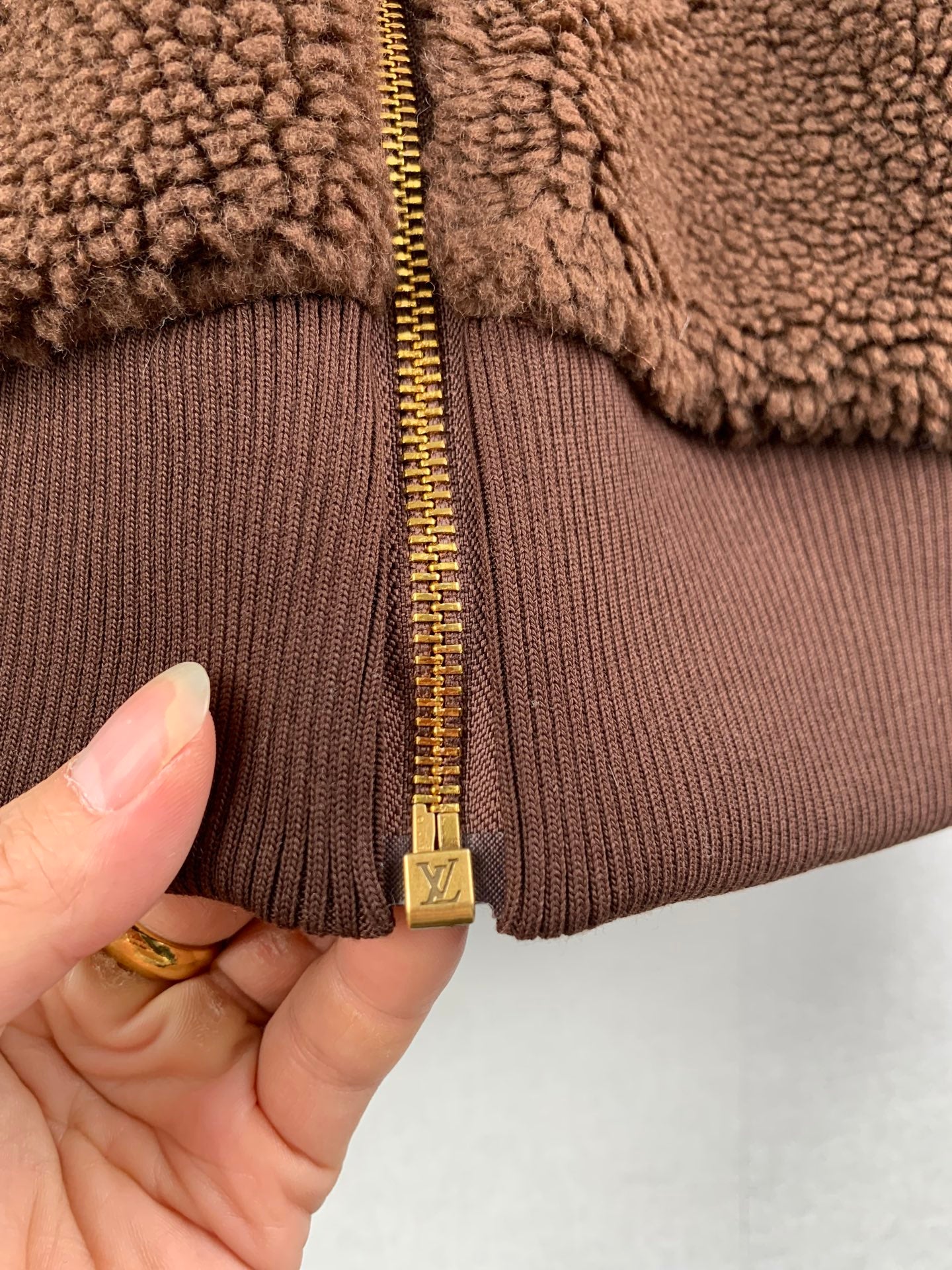 Louis Vuitton long jacket close-up: brown ribbed cuffs and gold zipper pull