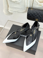 Chanel pointed-toe slingback pumps with black uppers and white tips, on a box