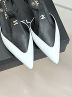 Chanel close-up of black and white pointed slingback pumps with gold logo hardware