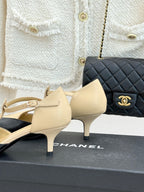 Beige pointed-toe slingback pumps with ankle straps and small heel, on box.