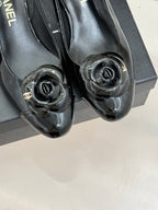 Pair of black patent leather flats with round CC medallion caps and glossy finish