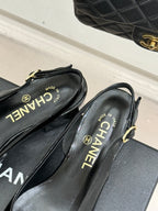 Black patent leather flat shoes with CHANEL logo insoles and gold-tone heel straps