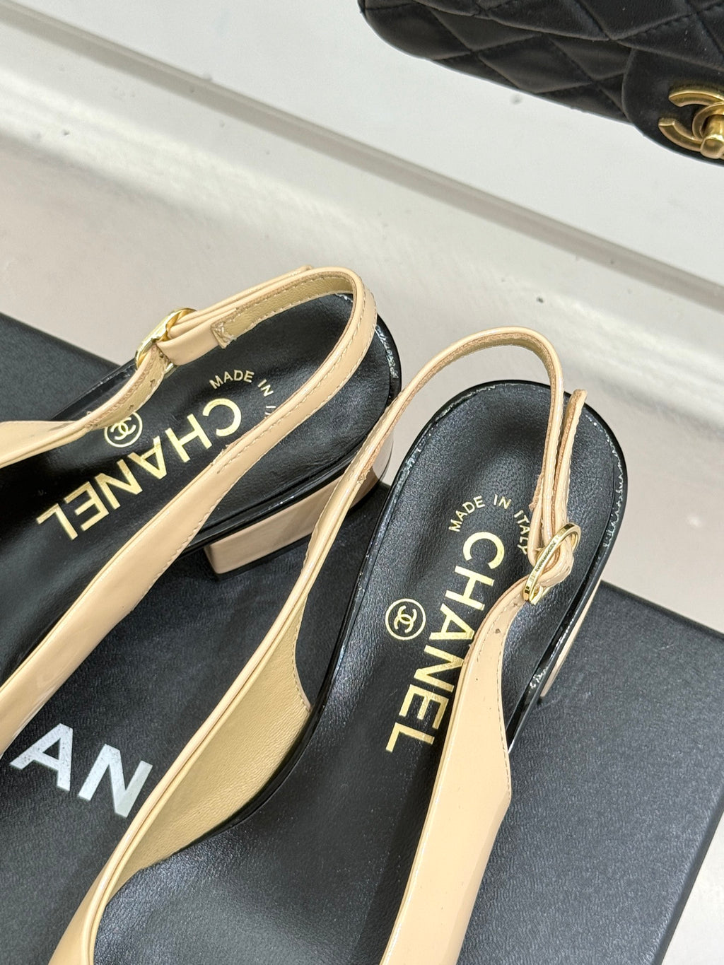 Women’s Chanel slingback heels close-up, cream straps with black logo lining