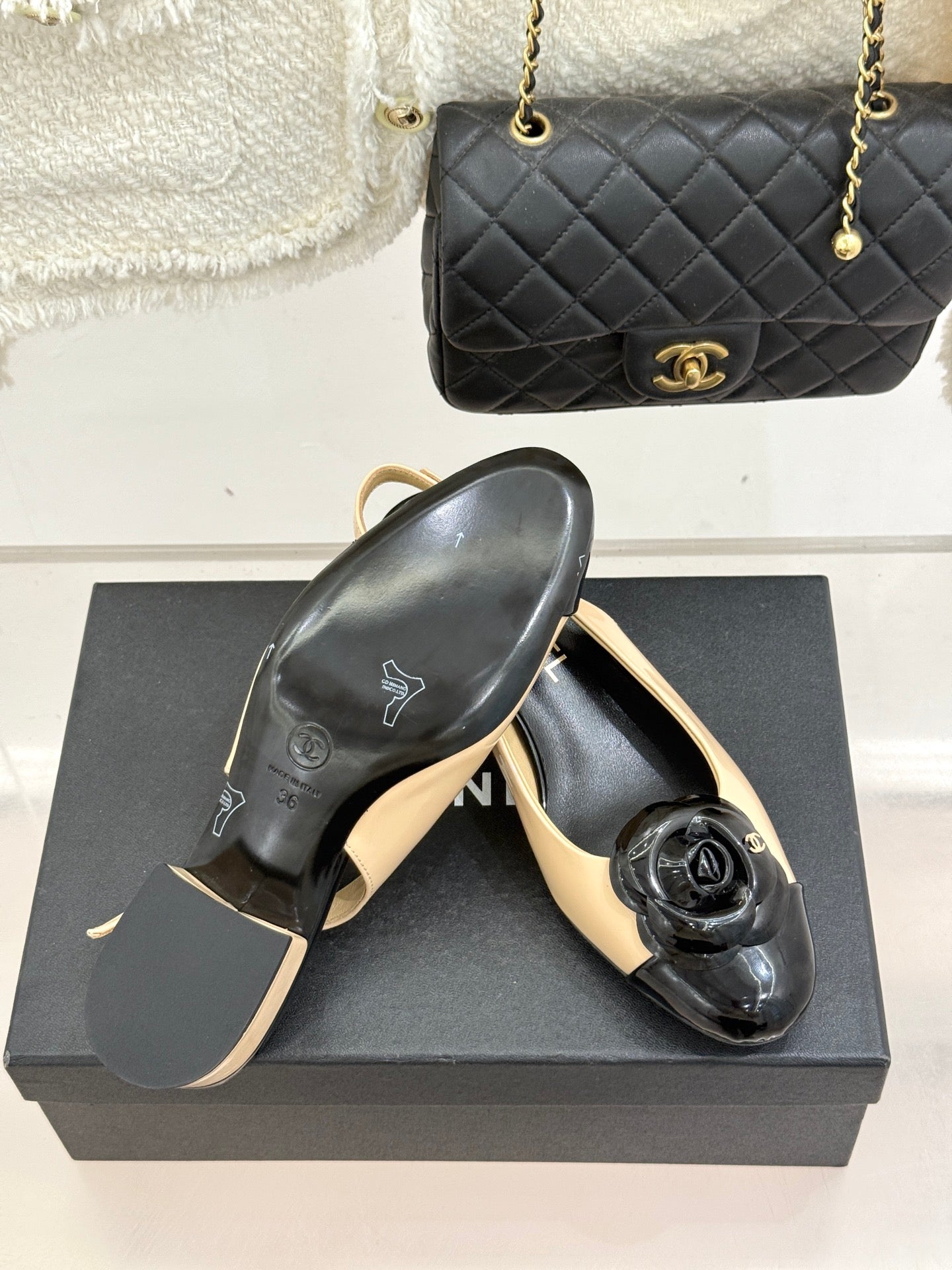 Women’s Chanel slingback heels, angled view showing black glossy toe and cream upper