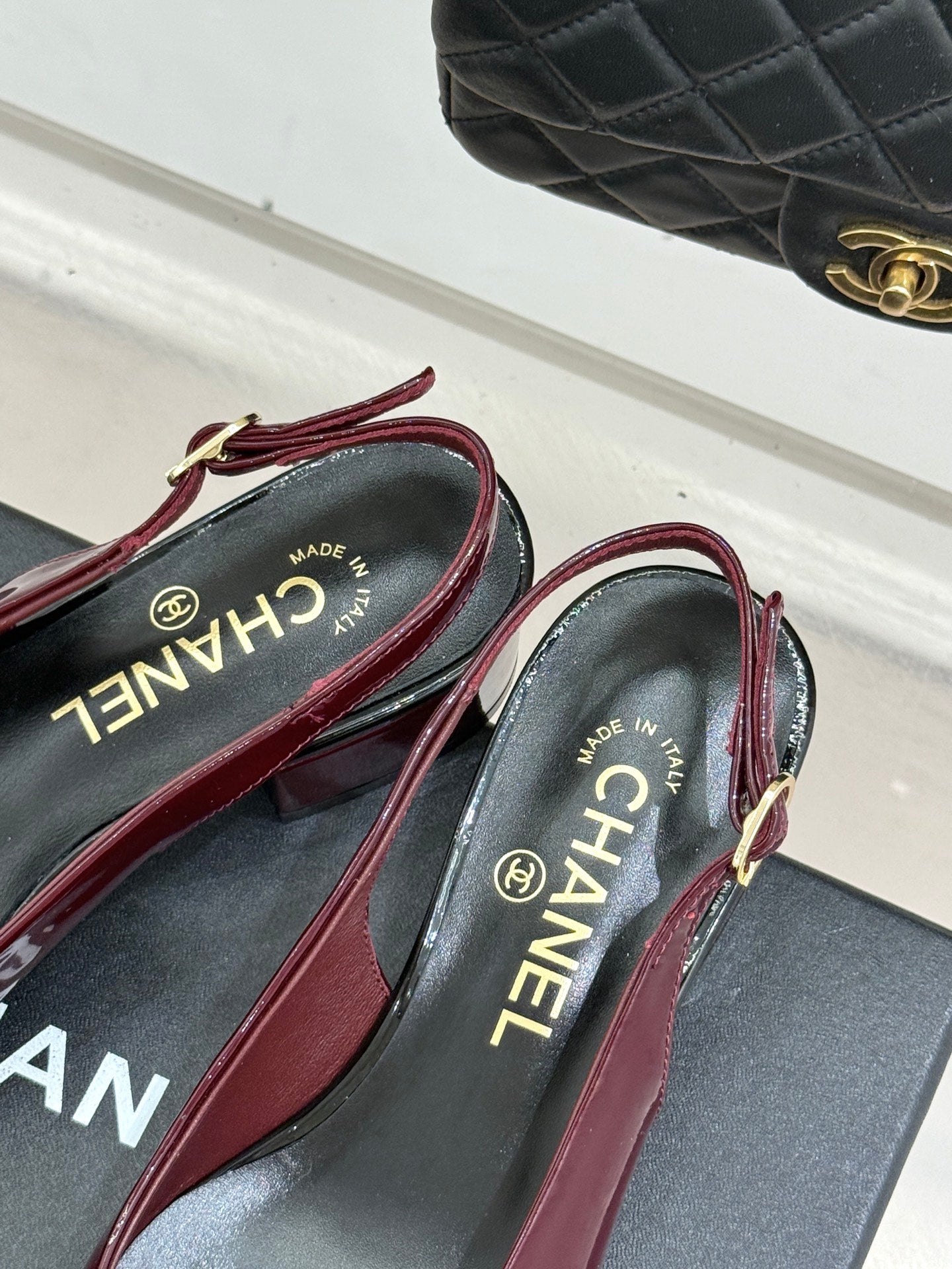 Burgundy patent flats with black CC toe emblem and CHANEL logo insoles