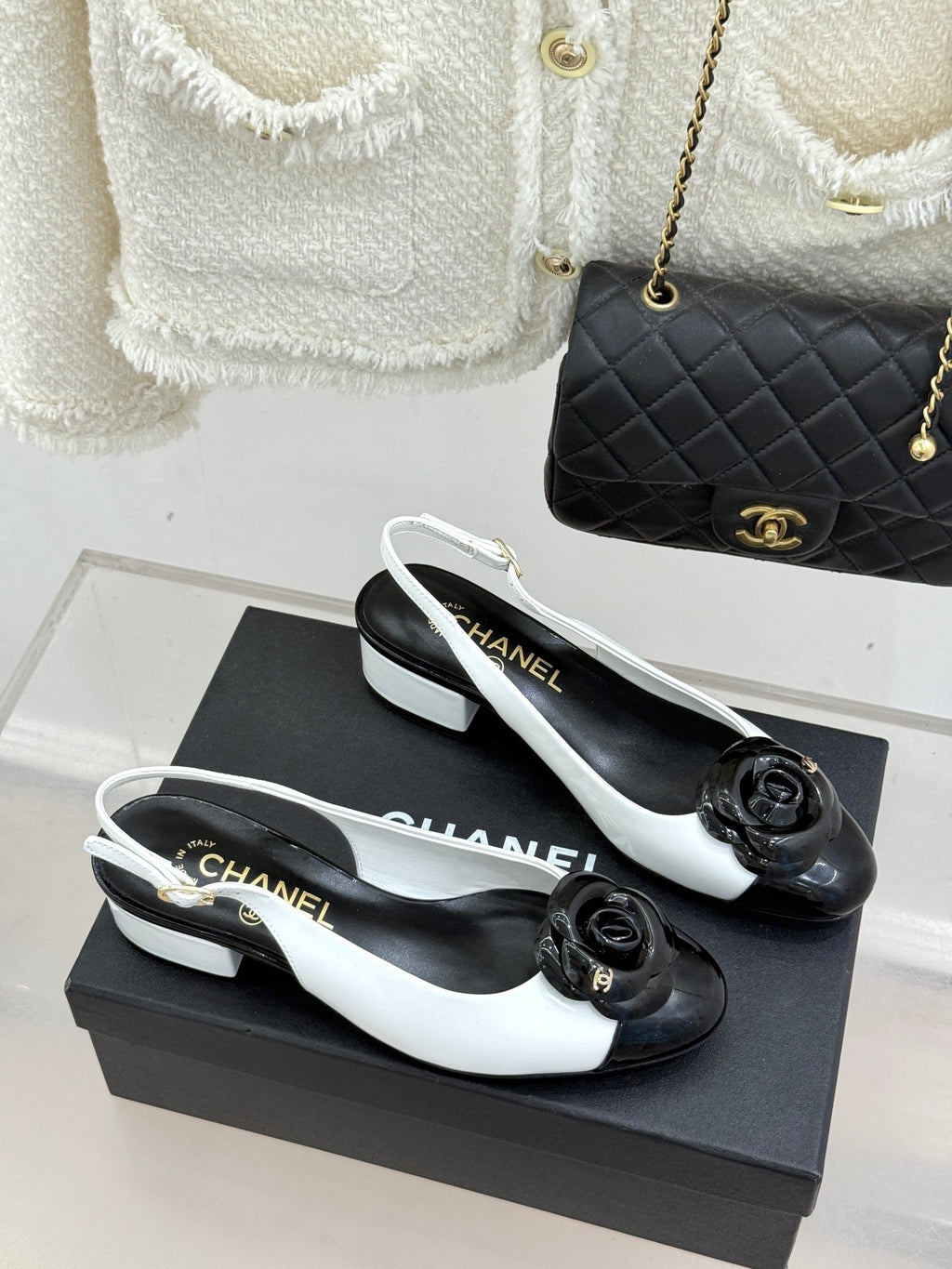 White slingback flats with black toe cap and rose bow detail