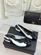 White slingback flats with black toe cap and rose bow detail