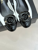 Black-and-white slingback pumps with rose emblem at the toe