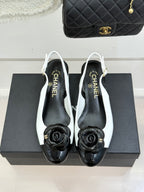 White slingback pumps with black toe cap, rose emblem, and block heel