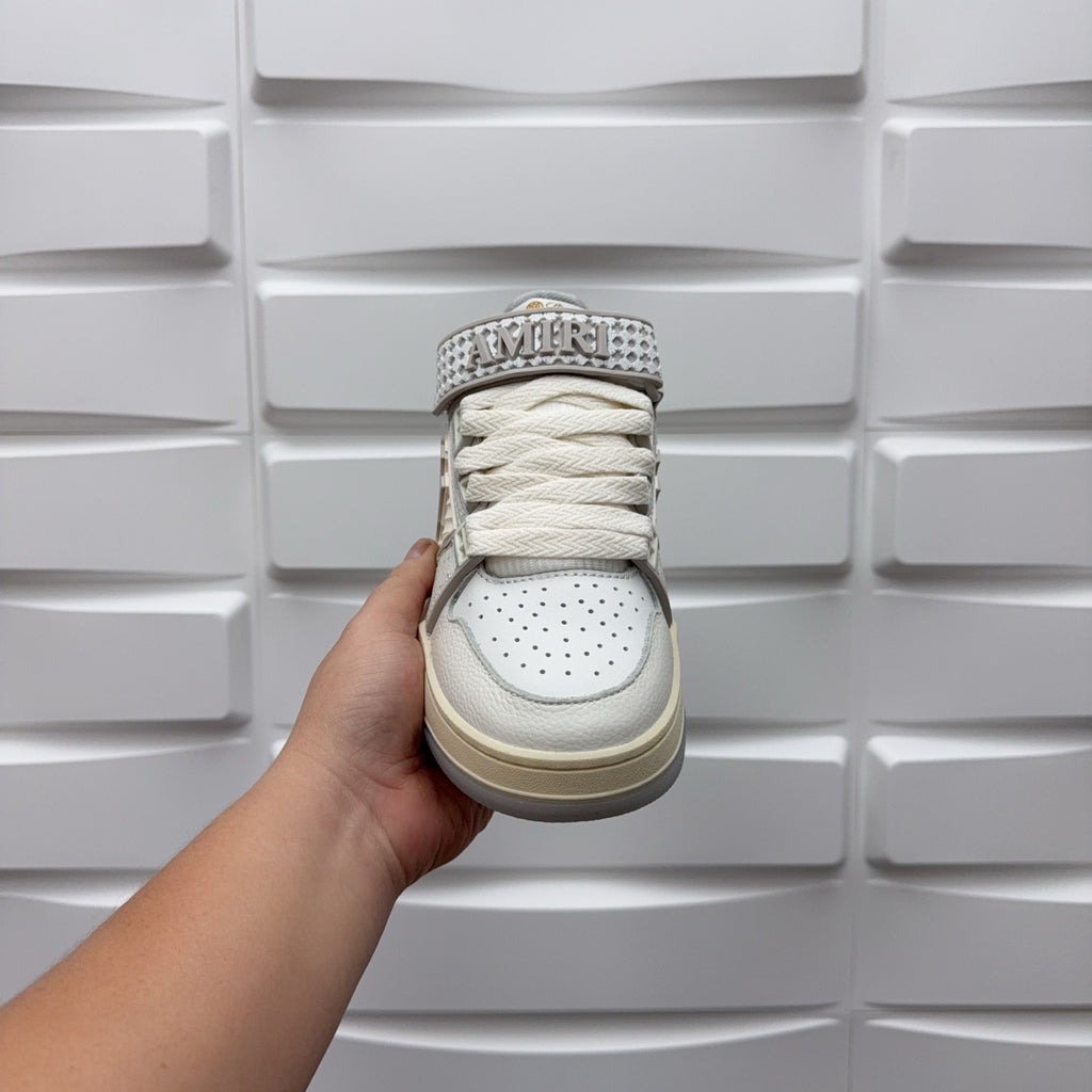 Amiri low-top sneaker held from heel, white leather with lace-up and logo tab