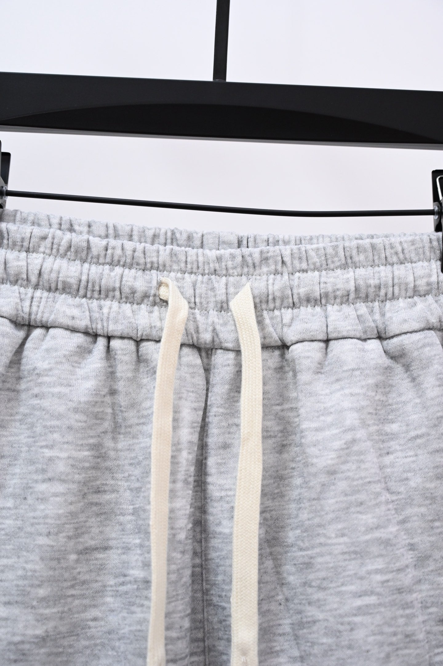 Gray sweatpants waistband with drawstring cords and elastic seam