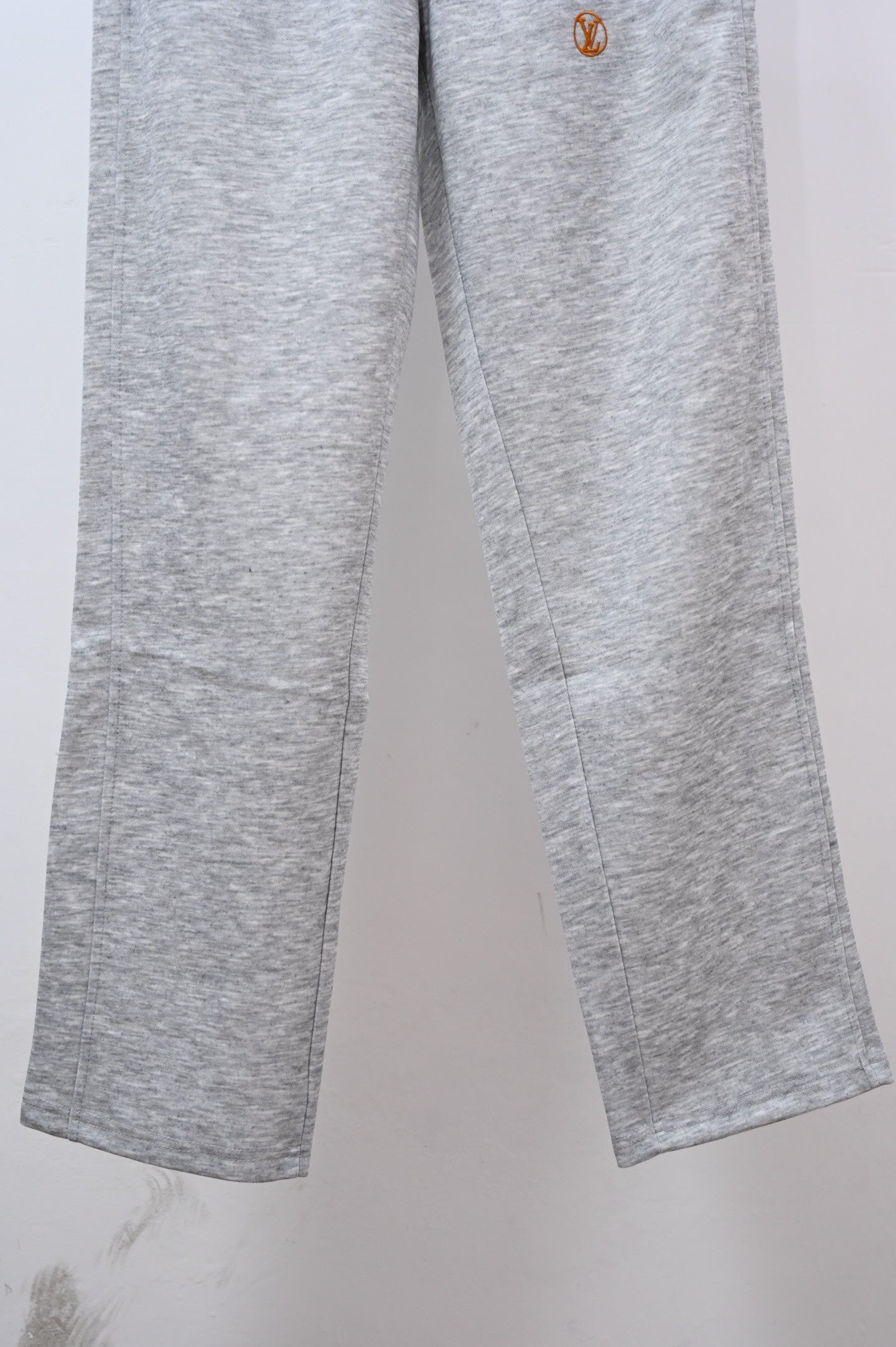 Gray sweatpants legs with small Louis Vuitton emblem