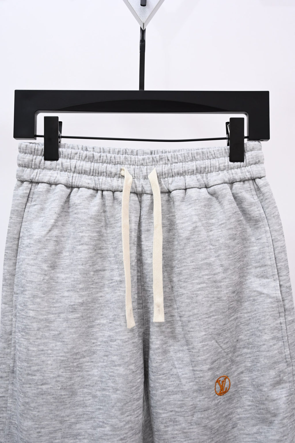 Gray drawstring sweatpants with elastic waistband, front view close-up