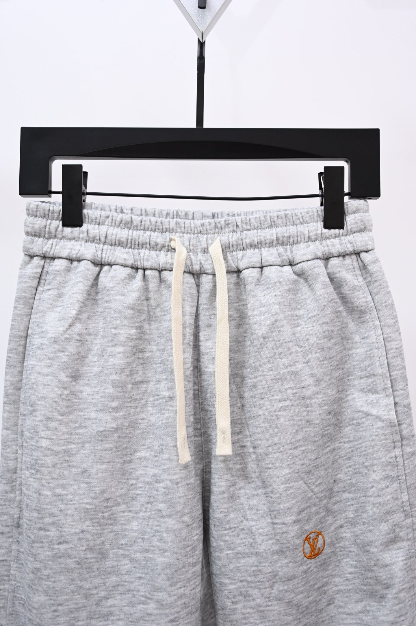Gray drawstring sweatpants with elastic waistband, front view close-up