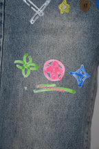 Denim pants close-up with colorful charm icons and small Louis Vuitton text