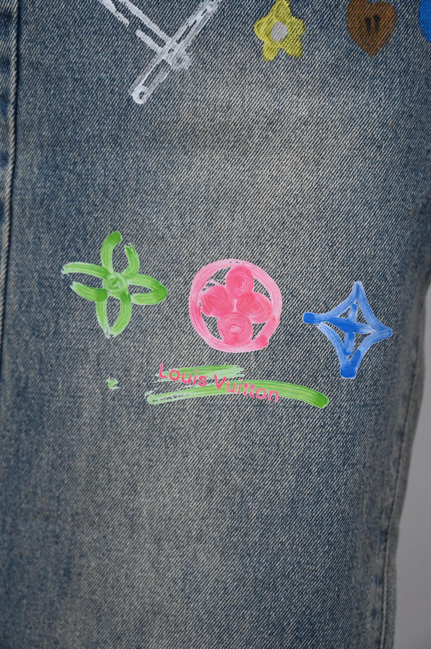Denim pants close-up with colorful charm icons and small Louis Vuitton text