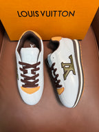 Pair of white Louis Vuitton sneakers with brown laces, yellow trims, and side LV emblem