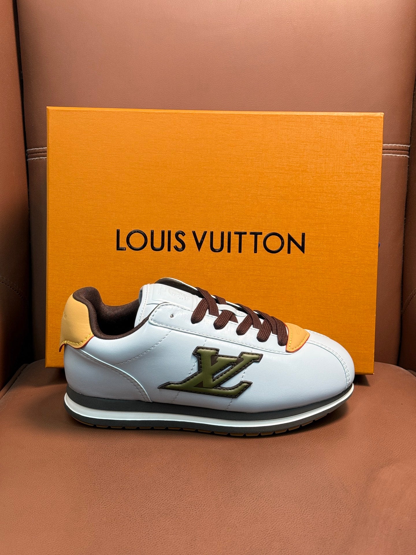 White Louis Vuitton low-top sneaker with brown laces, yellow accent patch, and green logo detail