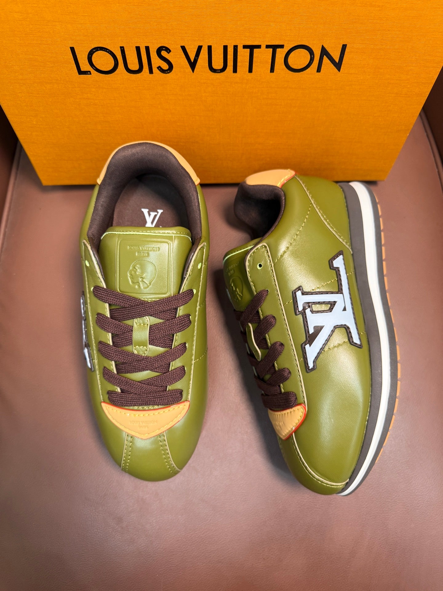 Green low-top sneakers with dark brown laces, LV logo, and white midsole