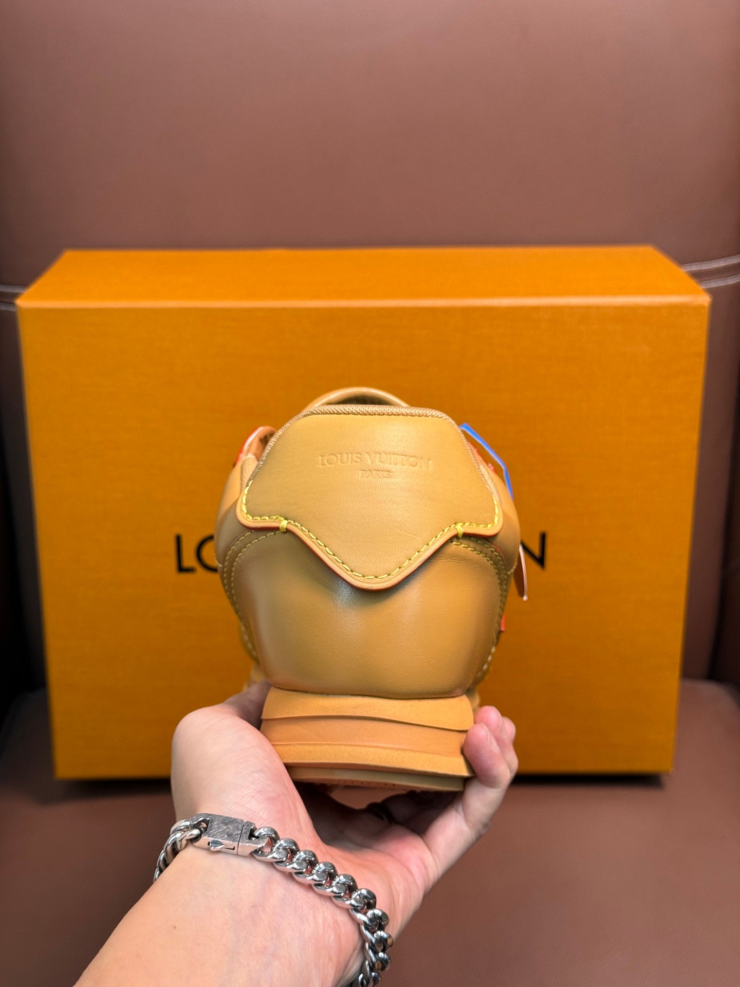 Louis Vuitton luxury sneakers in light tan, heel view held in hand