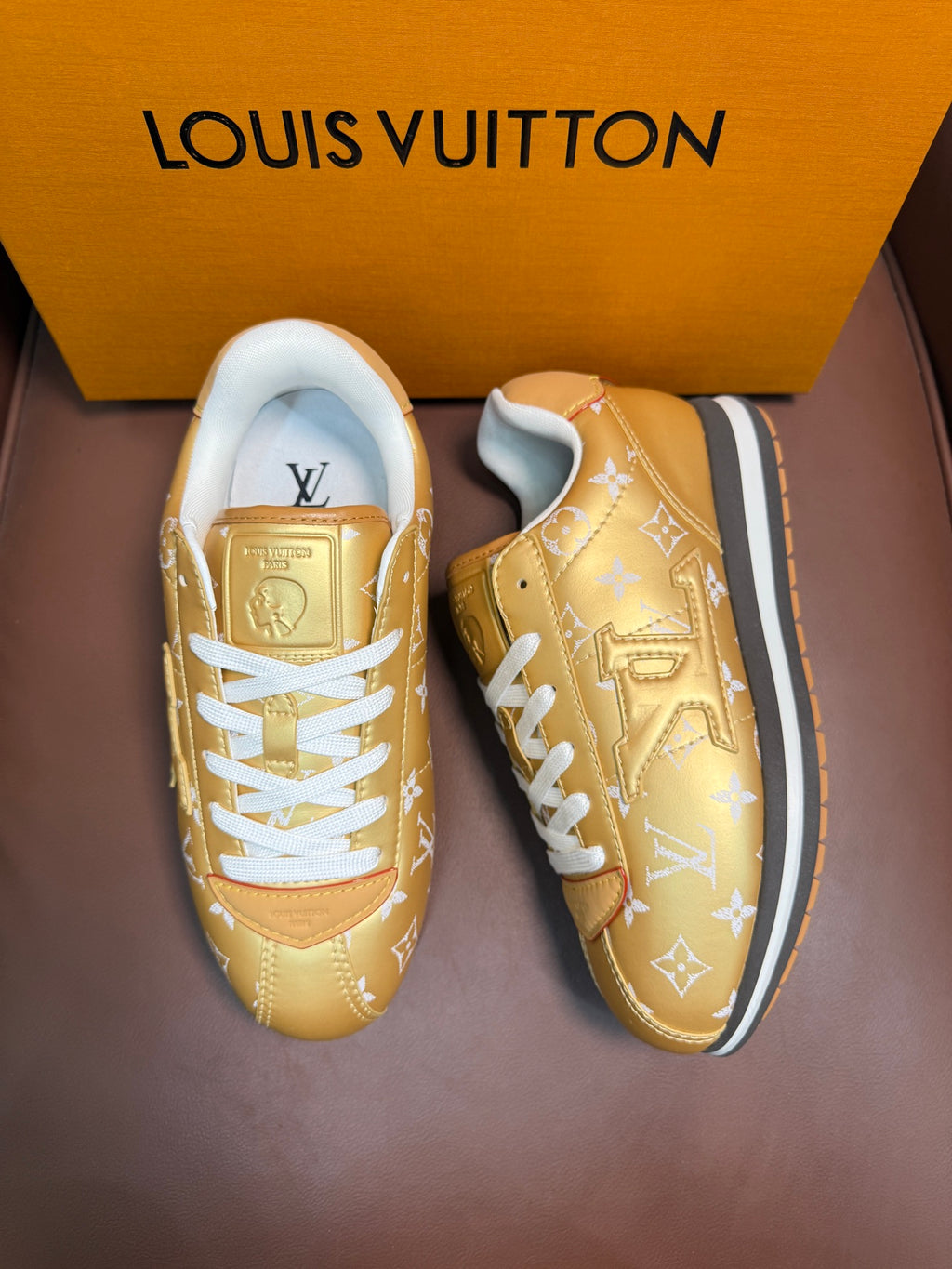 Gold monogram sneakers pair with white laces, side view, blue-trim soles