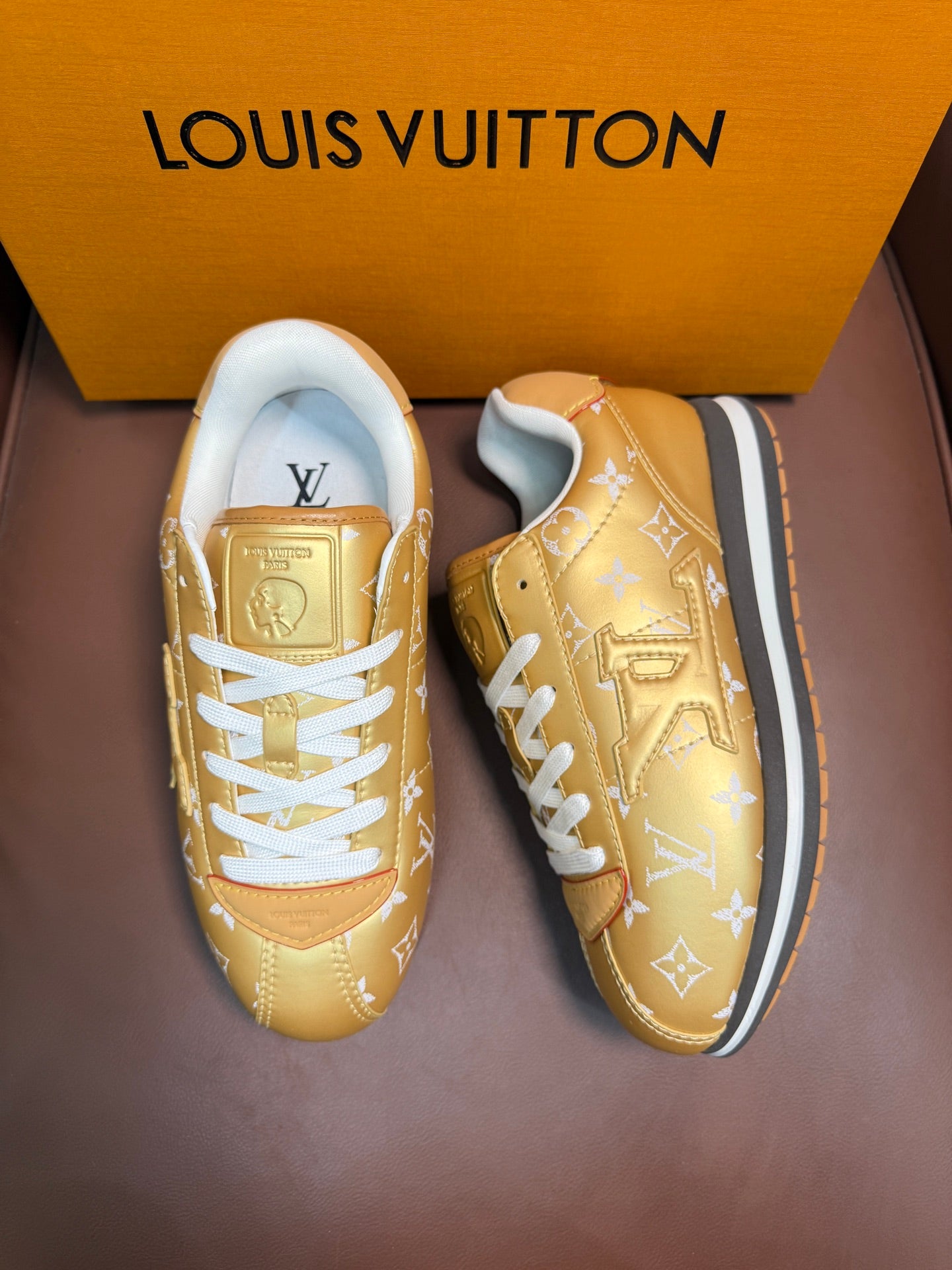 Gold monogram sneakers pair with white laces, side view, blue-trim soles