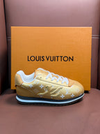 Gold monogram low-top sneakers with white laces and blue-trim sole, angled view