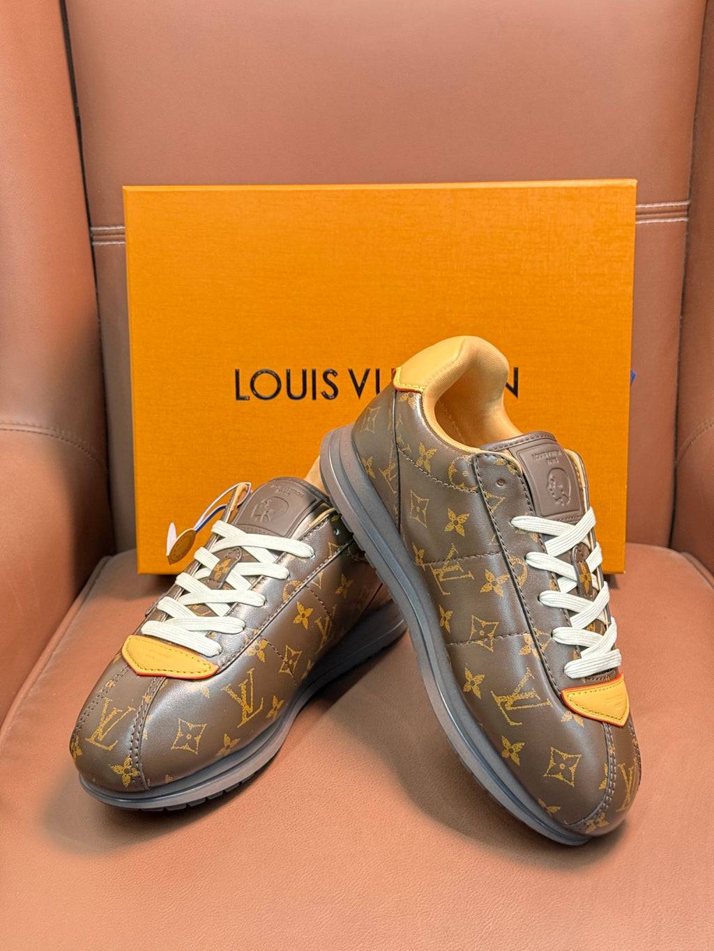Louis Vuitton monogram sneakers with white laces and tan accents, angled front view
