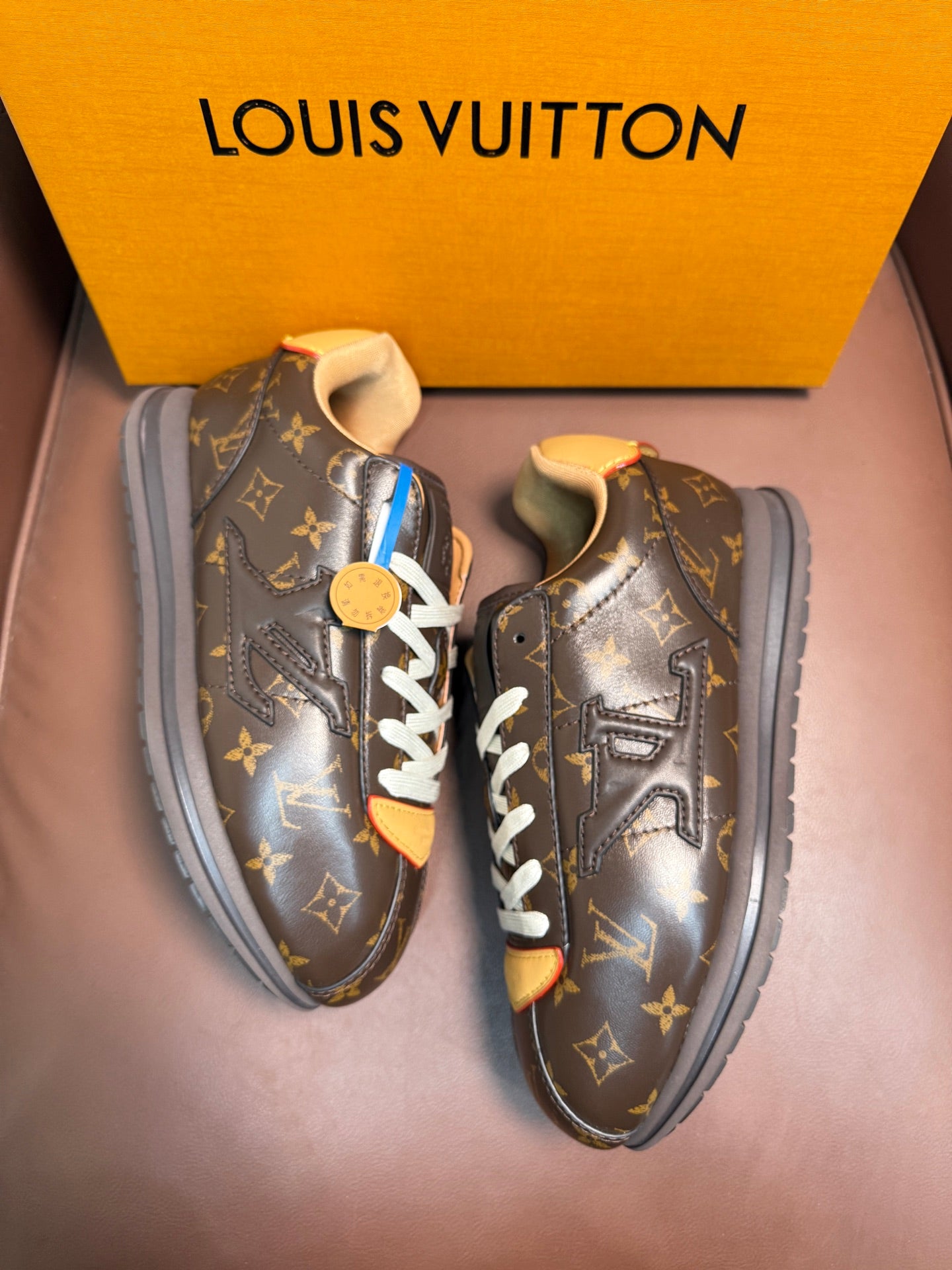 Louis Vuitton monogram sneakers with white laces and tan accents, side view