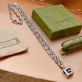 Silver chain necklace with square logo pendant and black enamel center