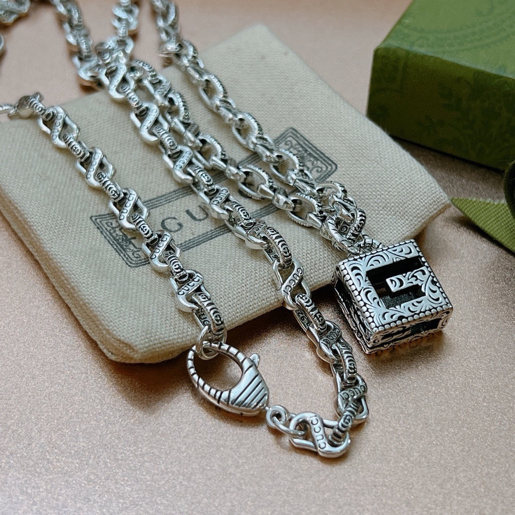 Silver charm necklace with square black enamel charm and ornate side links