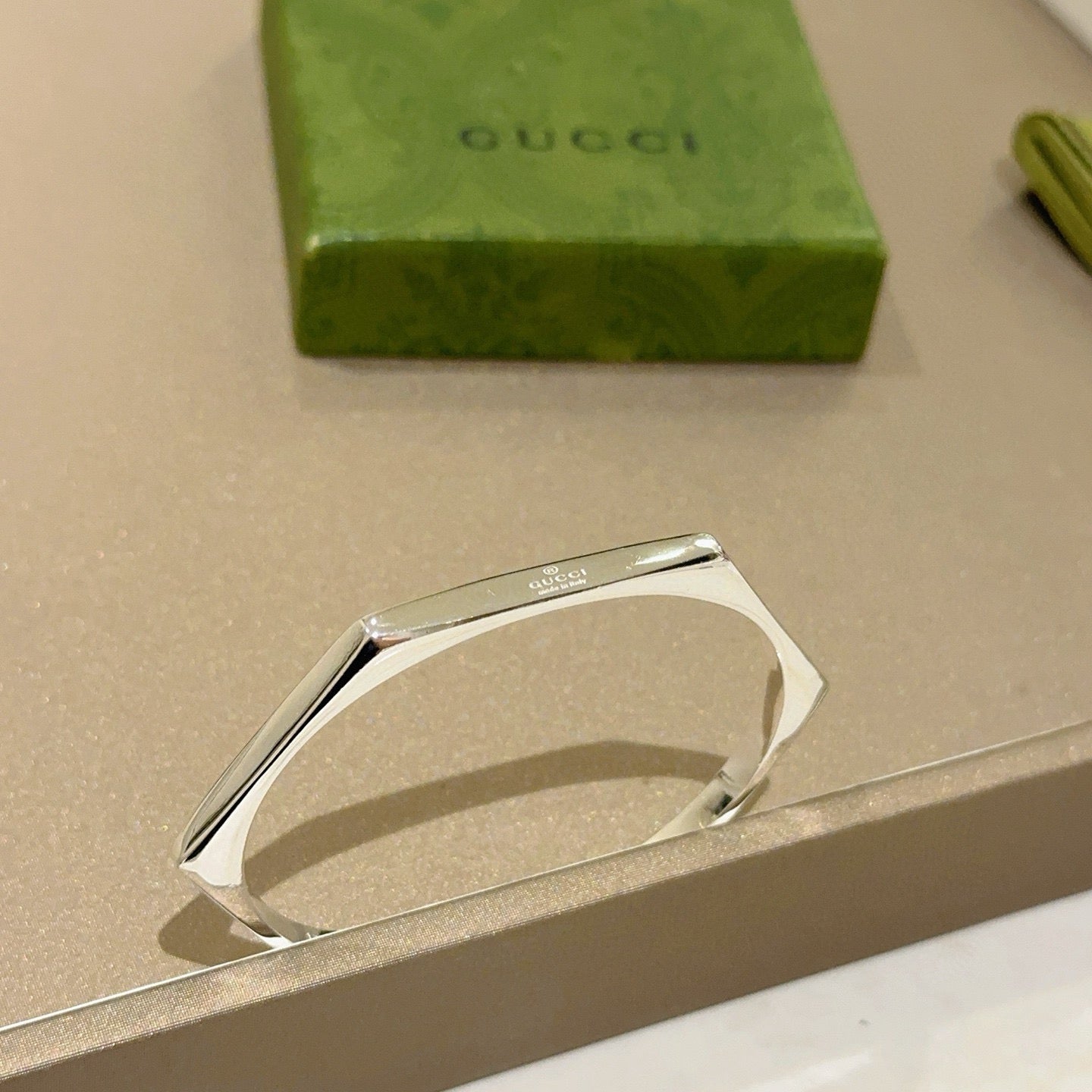 Gucci silver bangle bracelet with curved open design on jewelry card