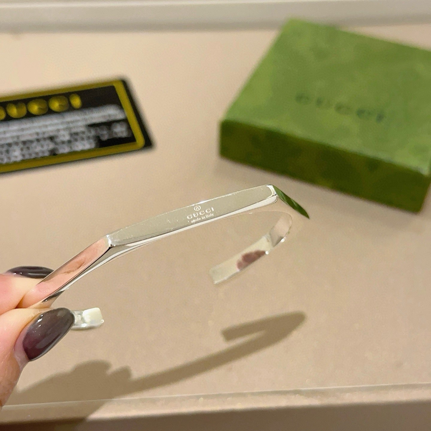 Gucci silver bangle side view on beige display card