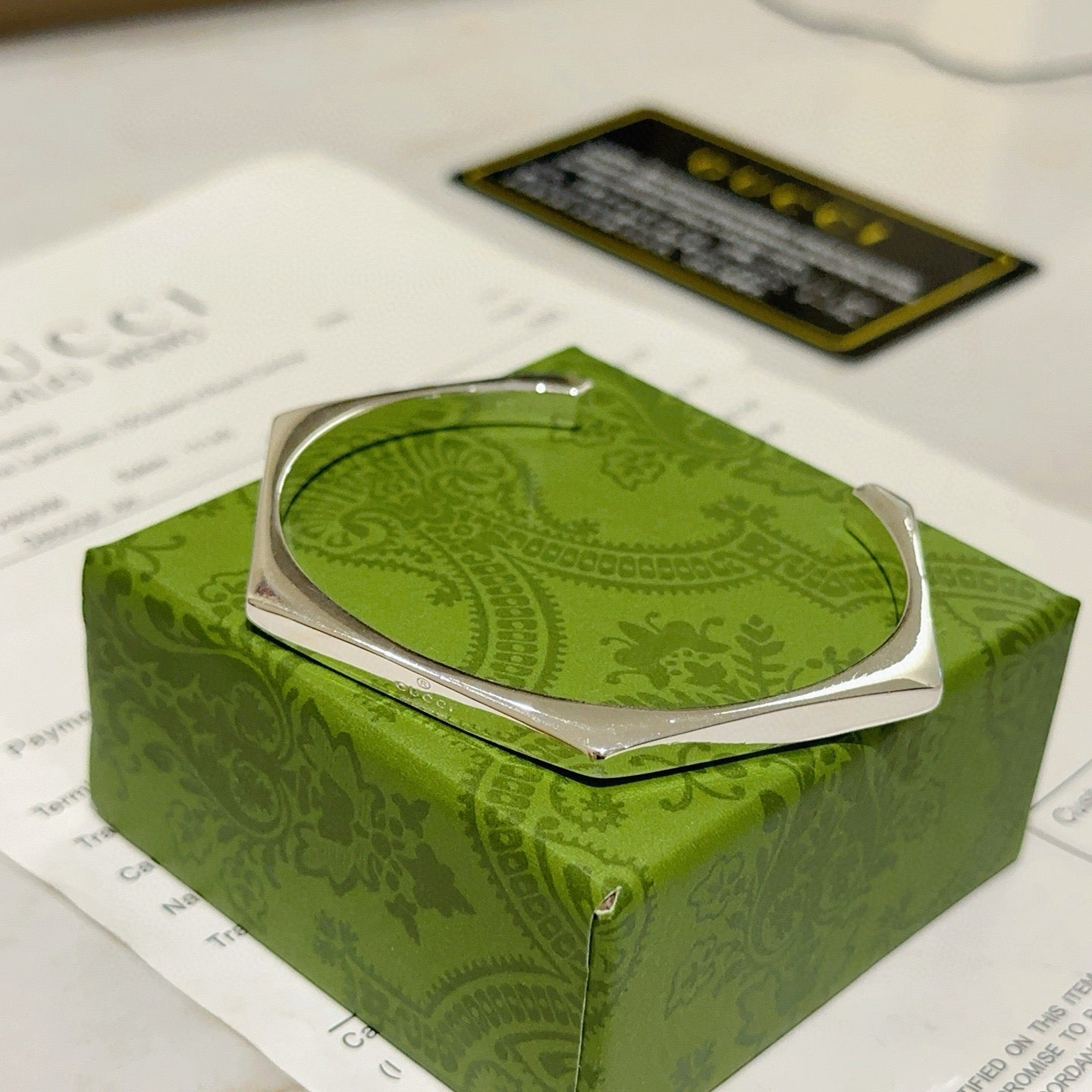 Gucci silver bangle bracelet on green box, front view
